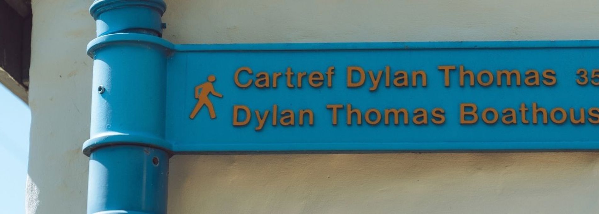 Blue fingerpost sign showing the direction and distance to the Dylan Thomas Boathouse