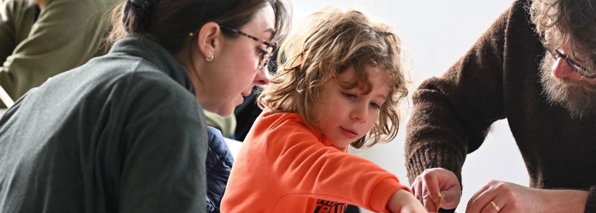Two adults and a child are making a toy rocket
