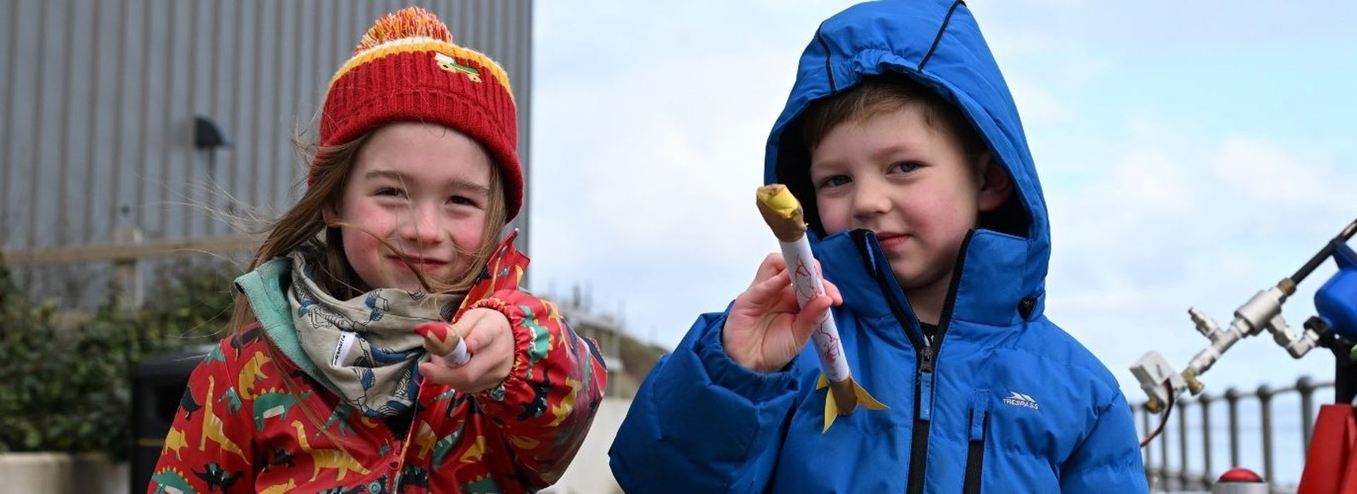 Two smiling children hold up mini rockets that they've made