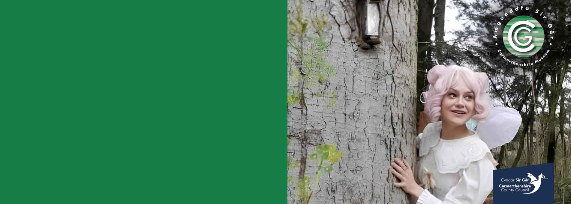 Woman dressed as a fairy looking out from behind a tree